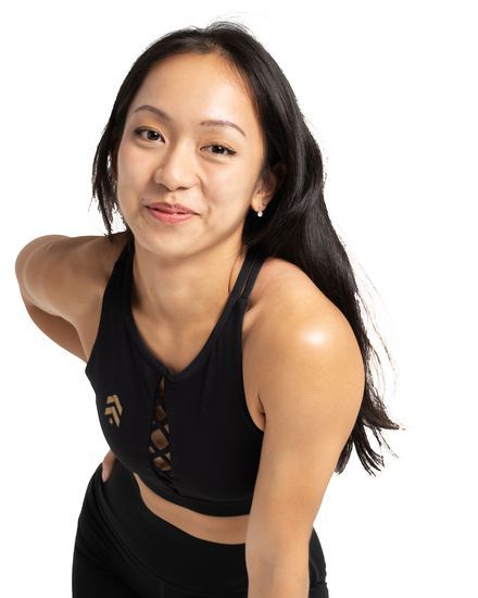 Mandalyn Tan leaning toward the camera with a hand on her knee, smiling
