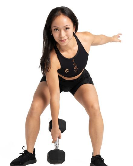 Mandalyn Tan lifting a hex dumbbell in a wide stance, one arm out for balance